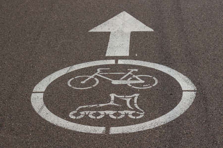 Arrow and sign Bike and Roller skates painted on the asphalt. Sidewalk for sportsmen. White road...