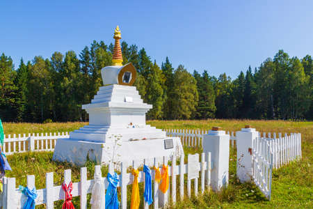 Summer view on White Buddhist Stupa of an Enlightenment decorated with colorful buddhist prayer scarves with traditional prayer texts in Sanskrit. Translation: Buddhist Bodhi Stupaの写真素材