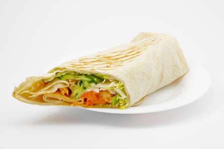 Doner kebab or Gyros food or Shawarma on white plate isolated on white background. Sandwich roll from tortilla bread filled with grilled meat, cucumber, tomato and sauce. Popular fast foodの写真素材
