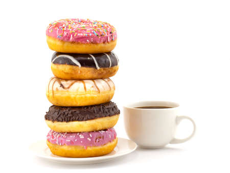 Big stack of assorted colorful donuts with various decoration and small cup of black coffee isolated on a white background. Concept background of world problem of obesity and unhealthy nutritionの写真素材