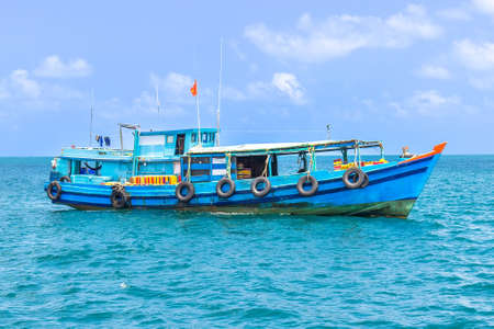 Wooden vietnamese fishing boat at blue sea. Local fishing boat departs for fish and squid.の写真素材