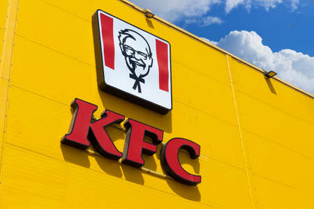 Krasnoyarsk, Russia - May 19, 2022: Red KFC restaurant logo on yellow facade building. KFC is a fast...