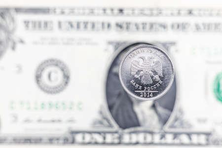 Coin 1 Russian ruble on blurred defocused background of american dollar banknote. Translation: One Ruble, Bank of Russiaの写真素材
