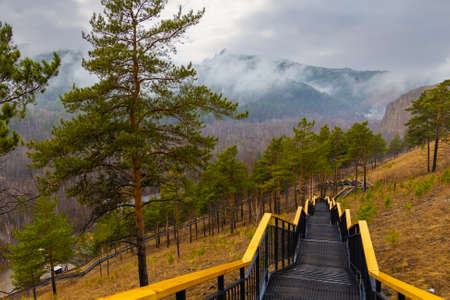 Tourist staircase in rainy springtime day on Torgashinsky ridge in Krasnoyarsk, Russia. Empty metal...