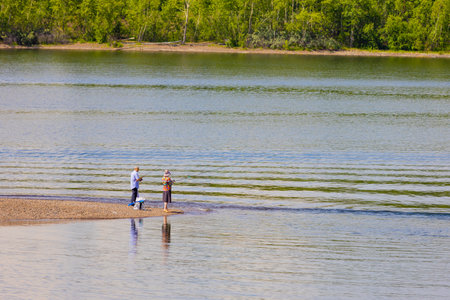 Krasnoyarsk, Russia - June 20, 2022: couple of fishermen on the Yenisei river. Elderly man and woman fishing with rodsのeditorial素材