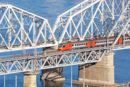 Passenger electrical train pass on railway bridge Yenisey river in Krasnoyarsk, Russia. Moving red passenger train on metal railroad bridgeの写真素材