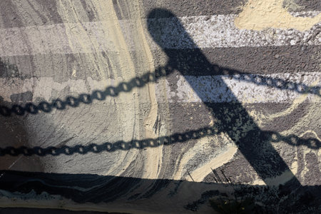 Clear shadow from the chain fence on the asphalt. Abstract stains from tree pollen on the road surfaceの写真素材
