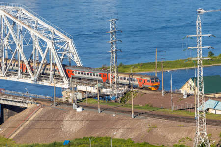Passenger electrical train moving on railway bridge Yenisey river in Krasnoyarsk, Russia. Commuter...