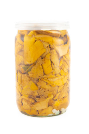 A jar of pickled chanterelles under a plastic lid isolated on a white background. Pickled mushrooms in glass jar. Homemade healthy food.の写真素材