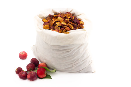 Fabric bag with dried apples isolated on white background. Still life with fresh ripe red small apples and big bag with dried sliced of apples. Homemade preparations for fruit compoteの写真素材