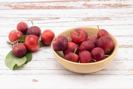 Fresh small apples in wooden bowl on white wooden table. wild red crabapples in bowlの写真素材
