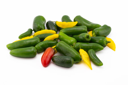Scattering of green jalapeno peppers and yellow lemon drops pepper isolated on white background.