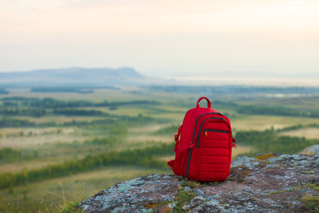 Red hiking backpack on the edge of the cliff. tourism travel background. Active trekking lifestyle. mountain and valley landscapeの写真素材