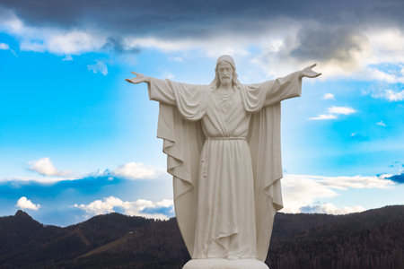 Krasnoyarsk, Russia - October 28, 2022: Jesus Christ statue with open arms near Church of the New Martyrs and Confessors of Russia. Monument against blue sky.のeditorial素材