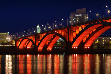 Krasnoyarsk, Russia - October 24, 2022: Night cityscape with Communal Bridge among Yenisey River and Big Ben Tower in Krasnoyarsk, Russia.のeditorial素材