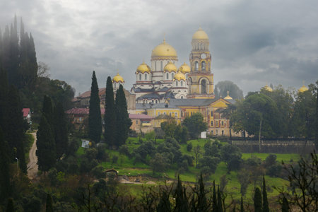 View on New Athos Monastery at rainy day. New Athos Monastery is a monastery in New Athos in the republic of Abkhazia. Golden domes of Panteleimon Cathedral are hidden by gray cloudsの写真素材