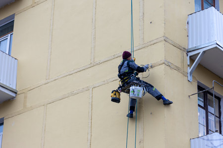 Moscow,Russia - 11 November, 2022: Worker assembler mounts iron elements on the wall of the building. Industrial climber without helmet working at height. Professional industrial mountaineering workerのeditorial素材