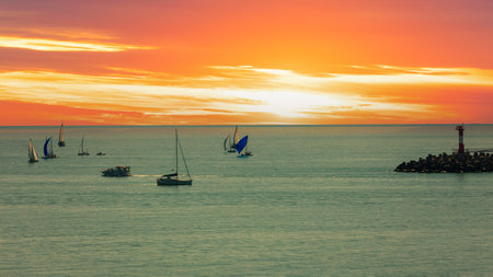 Seascape with sailing yachts in the sea at orange sunset. Advertising background for travel and cruisesの写真素材