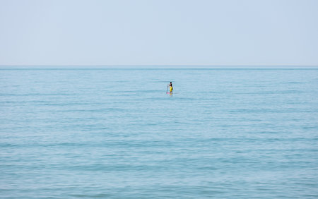 Distant unrecognizable woman on a SUP board floating on a stand up in the sea. Concept lifestyle...