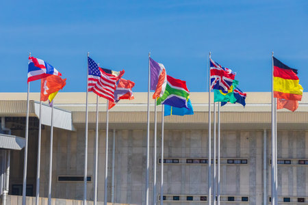 National flags of different countries fluttering in the wind against gray building and blue sky