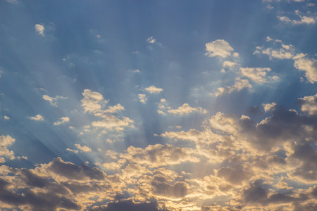 Evening sky with glowing clouds. Sunset sky with sun rays among fluffy clouds. Heaven background