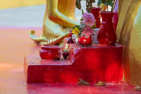 Offerings of incense sticks and flowers in red bowls for deity in Buddhist temple at Pattaya, Thailandの写真素材