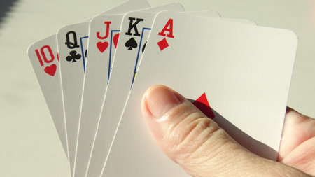 Playing cards in the hand of a man on a light background.