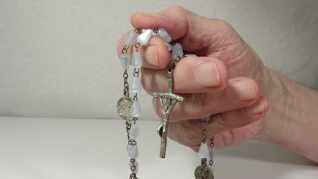 Female hands with rosary beads on a white background. Close-up.の写真素材