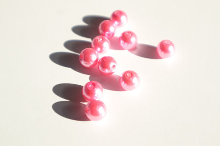 pink beads on a white background with a shadow from the sunの写真素材