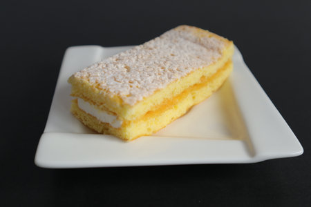 Cream cake on a white plate on a black background. Selective focus.の写真素材