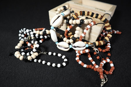 Set of different beads in a wooden box on a black background.の写真素材