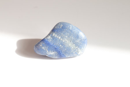 blue lace agate pebble stone on a white background with shadow and lightの写真素材
