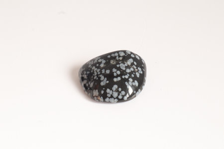 Snowflake obsidian macro shooting of natural mineral rock specimen - tumbled jasper gemstone on white backgroundの写真素材