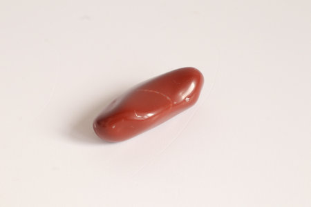 Close-up of a red semiprecious stone, dolomite gemstone on a white background with copy spaceの写真素材