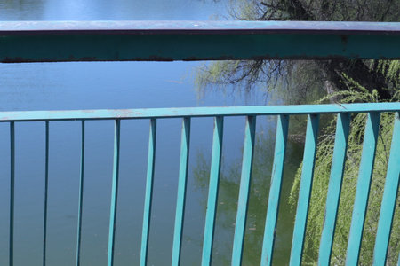 green metal fence on the bank of the lake, closeup of photoの写真素材