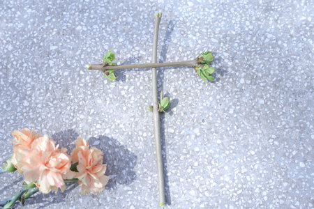 Carnation flower and cross on the ground. Symbol of faith.の写真素材