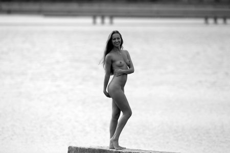 A beautiful girl outdoors enjoys nature. Beautiful young sexy naked woman by the water.の写真素材
