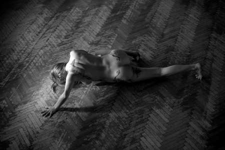 Sexy nude woman laying down on a wooden floor.の写真素材