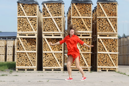 Jumping beautiful woman in red dress, firewood background