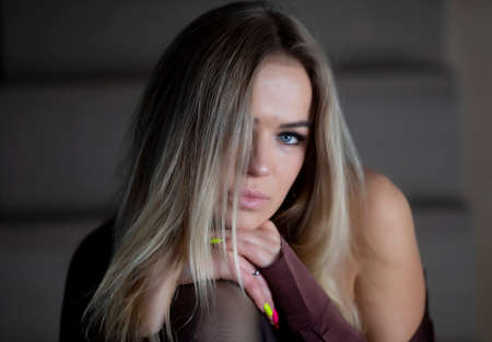 Sensual, attractive young woman in silk pajamas and black socks posing on a chairの写真素材