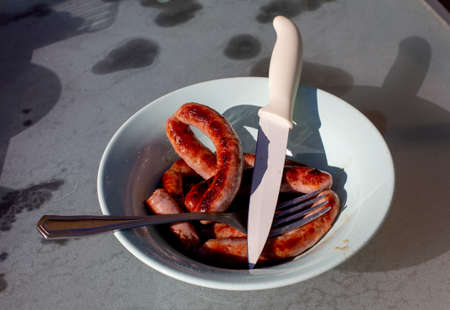 Grilled sausages and fresh roasted vegetables on a plate on the table.の写真素材