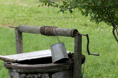 Rustic wooden water well with woodpile of firewoodの写真素材