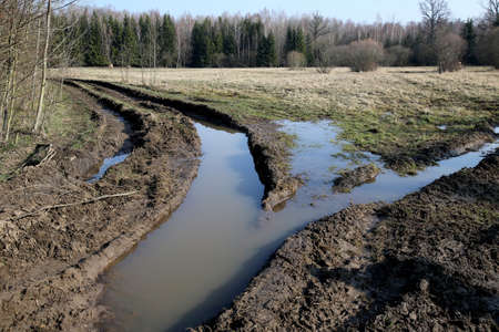 Tractor tracks on wet ground. Damaged fields cultivated by farmers