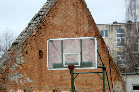 A basketball board in the background of an abandoned house