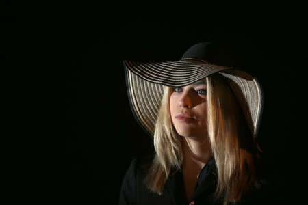 Beautiful Woman in big black hat on dark background