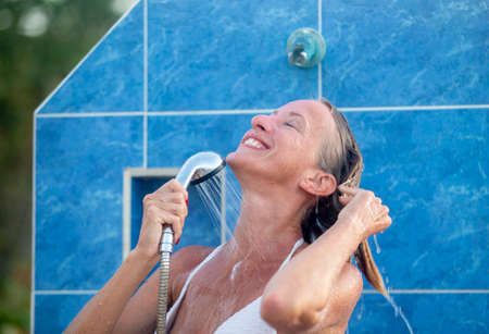 Portrait of a young woman wearing a bikini standing in an outdoor shower