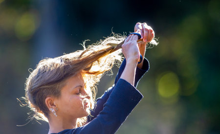 A young woman is cutting her hair, an act of protestの写真素材