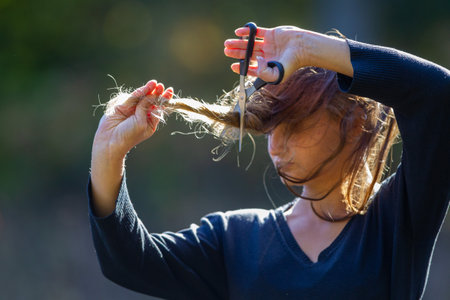 A young woman is cutting her hair, an act of protestの写真素材