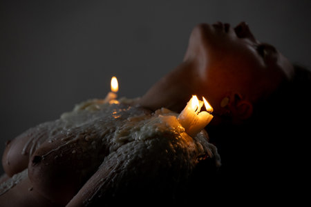 Burning candles in the dark on the girl's shoulderの写真素材