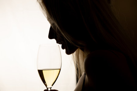Woman drinking white wine, silhouette with glassの写真素材
